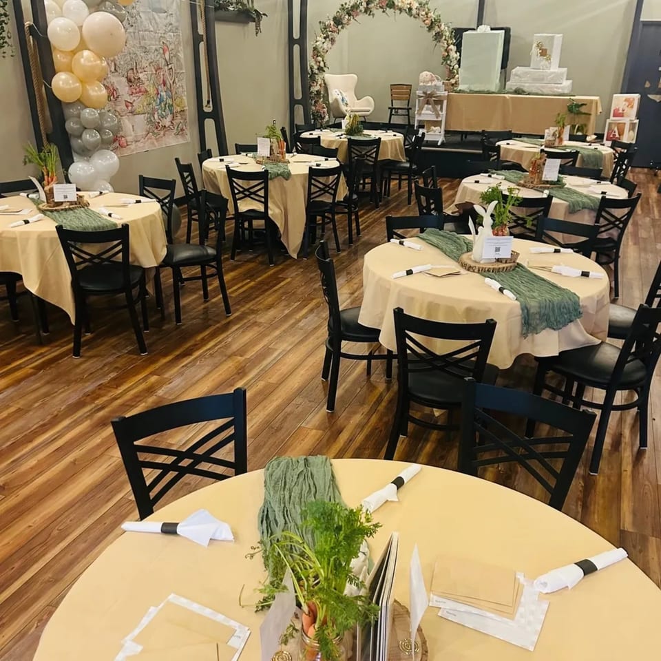 An Anchor Point Bistro dining room set up for an event with round tables, black chairs, and festive decorations.